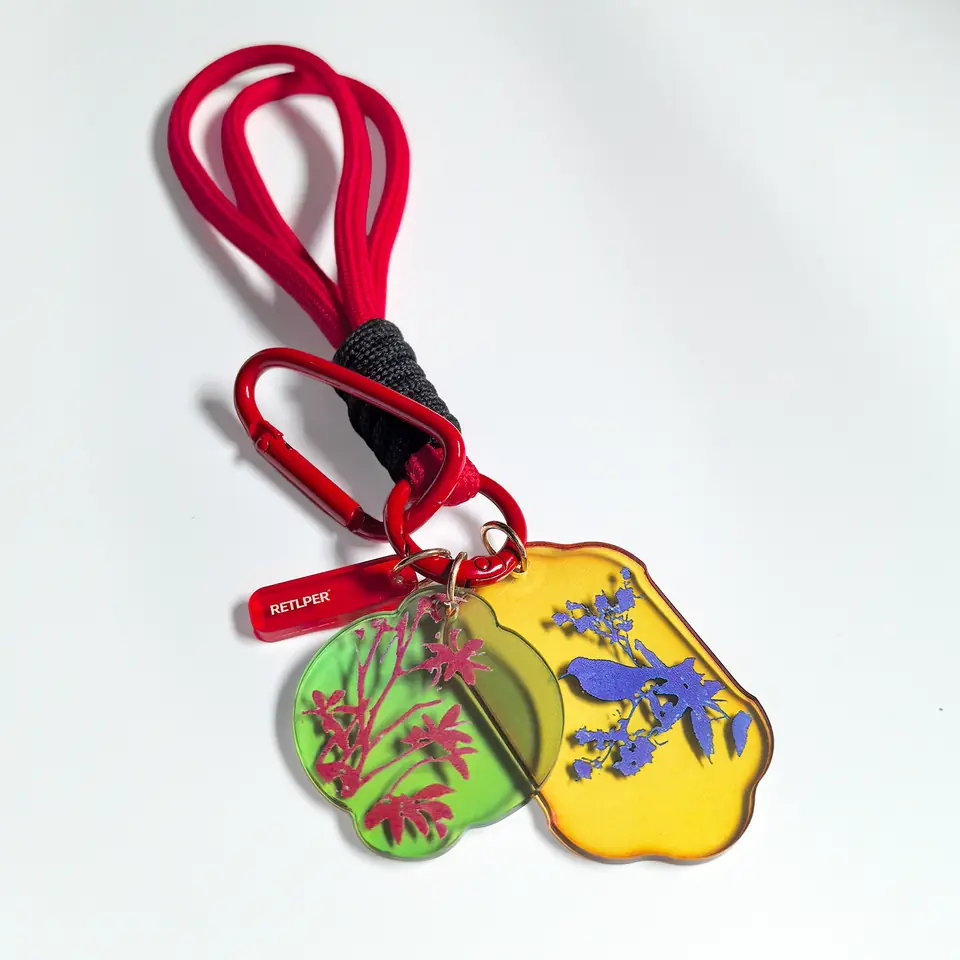 Complete RETLPER floral and bird acrylic keychain with red strap and clip on a white background